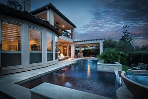 Luxury De La Garza Pool with modern spa, pergola, and evening backyard lighting